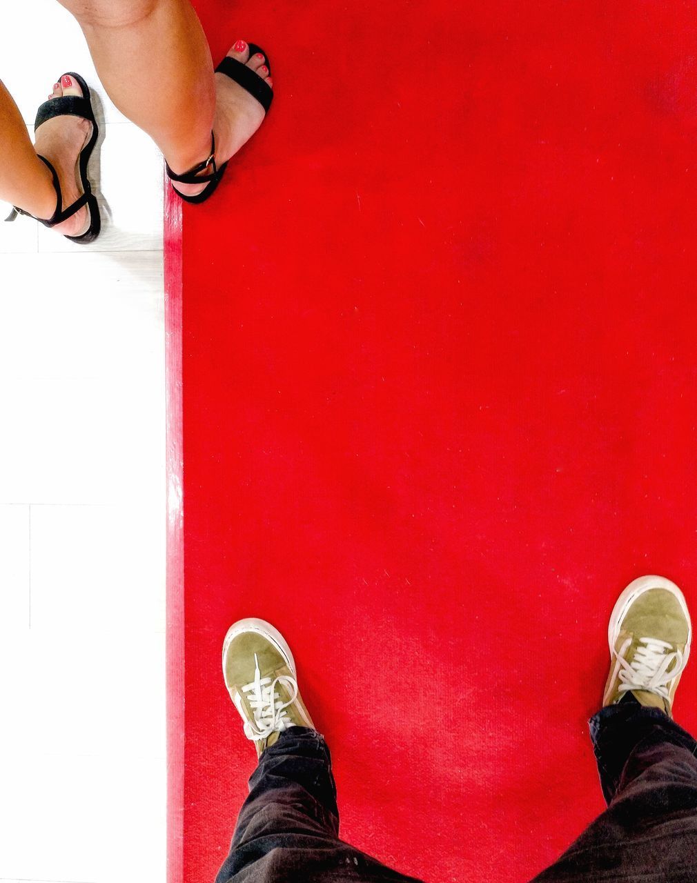 LOW SECTION OF MAN WEARING RED SHOES STANDING AGAINST WALL