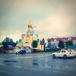 Cars on road against cloudy sky