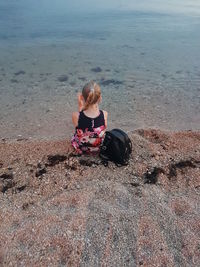 Rear view of girl sitting on shore at beach