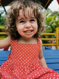 Little girl playing on the playground looking and laughing at camera.