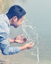 Young man washing face at lakeshore