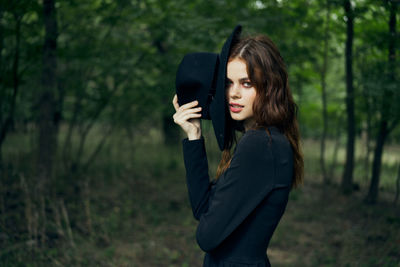 Young woman standing against trees