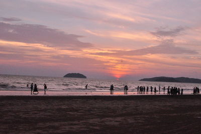 People on beach against sky during sunset