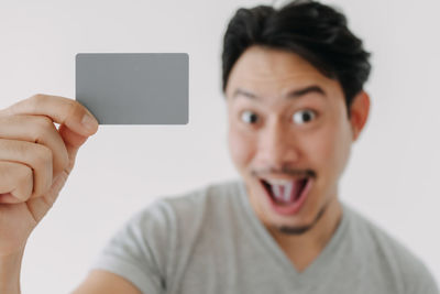 Portrait of young woman holding smart phone against white background