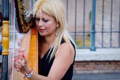 Portrait of woman playing harp on city street