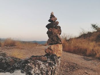 Stack of rocks on field against clear sky