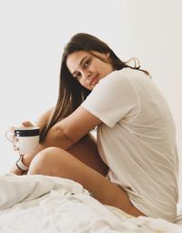 Young woman drinking coffee cup on bed