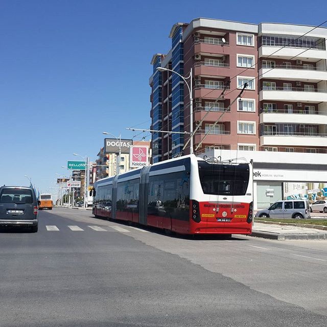 transportation, car, land vehicle, mode of transport, building exterior, architecture, built structure, road, street, city, clear sky, road marking, traffic, on the move, travel, city street, day, vehicle, city life, outdoors