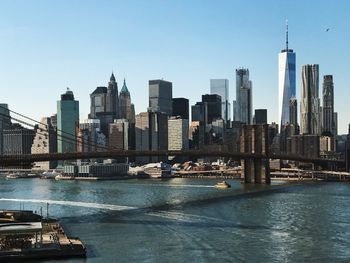 Brooklyn bridge and east river against sky in city