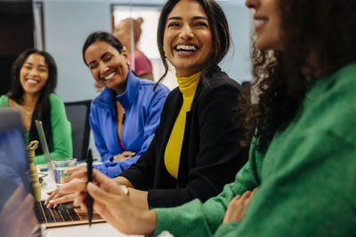 Happy female business professional with colleague during meeting at work place