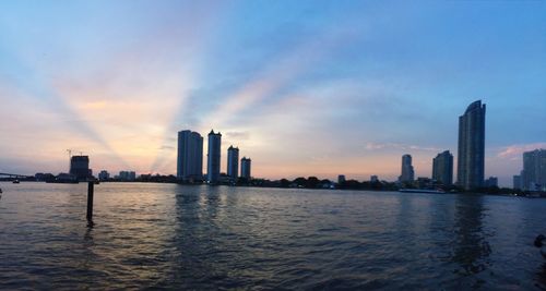 Sea and buildings against sky during sunset