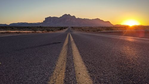 Road by mountains against sky during sunset