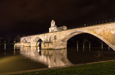 Arch bridge over river against sky at night