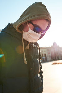 Young man wearing sunglasses standing against sky in city