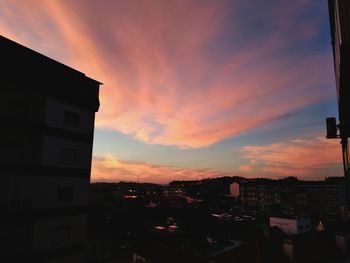 Silhouette houses against sky during sunset