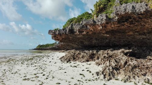 Rock formation on beach against sky