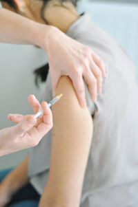 Cropped image of doctor injecting patient at hospital