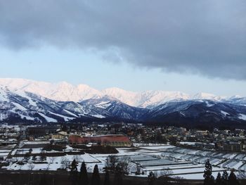 Houses by snowcapped mountains against sky