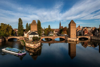 Arch bridge over river by buildings against sky