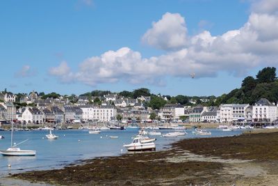 Sailboats moored on sea by buildings against sky