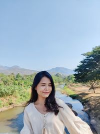 Portrait of smiling young woman standing on mountain against sky