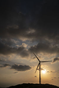 Low angle view of silhouette wind turbine against sky during sunset