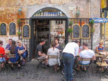 People sitting in restaurant against buildings in city