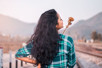 Side view of young woman standing against the sky