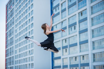 Woman jumping against buildings in city