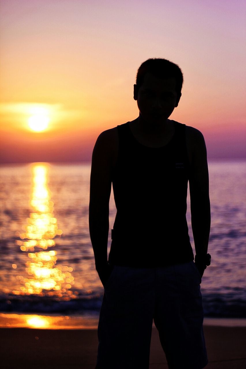 sunset, sea, water, orange color, standing, lifestyles, sun, horizon over water, silhouette, beach, leisure activity, sky, three quarter length, rear view, beauty in nature, scenics, shore, tranquil scene