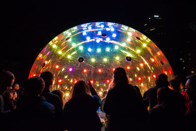 Rear view of people standing by large illuminated ball in nightclub