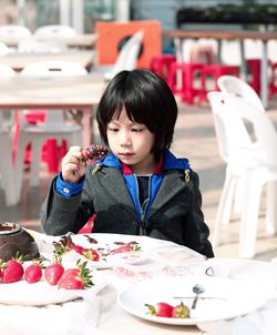 Young child holding chocolate covered strawberry at table