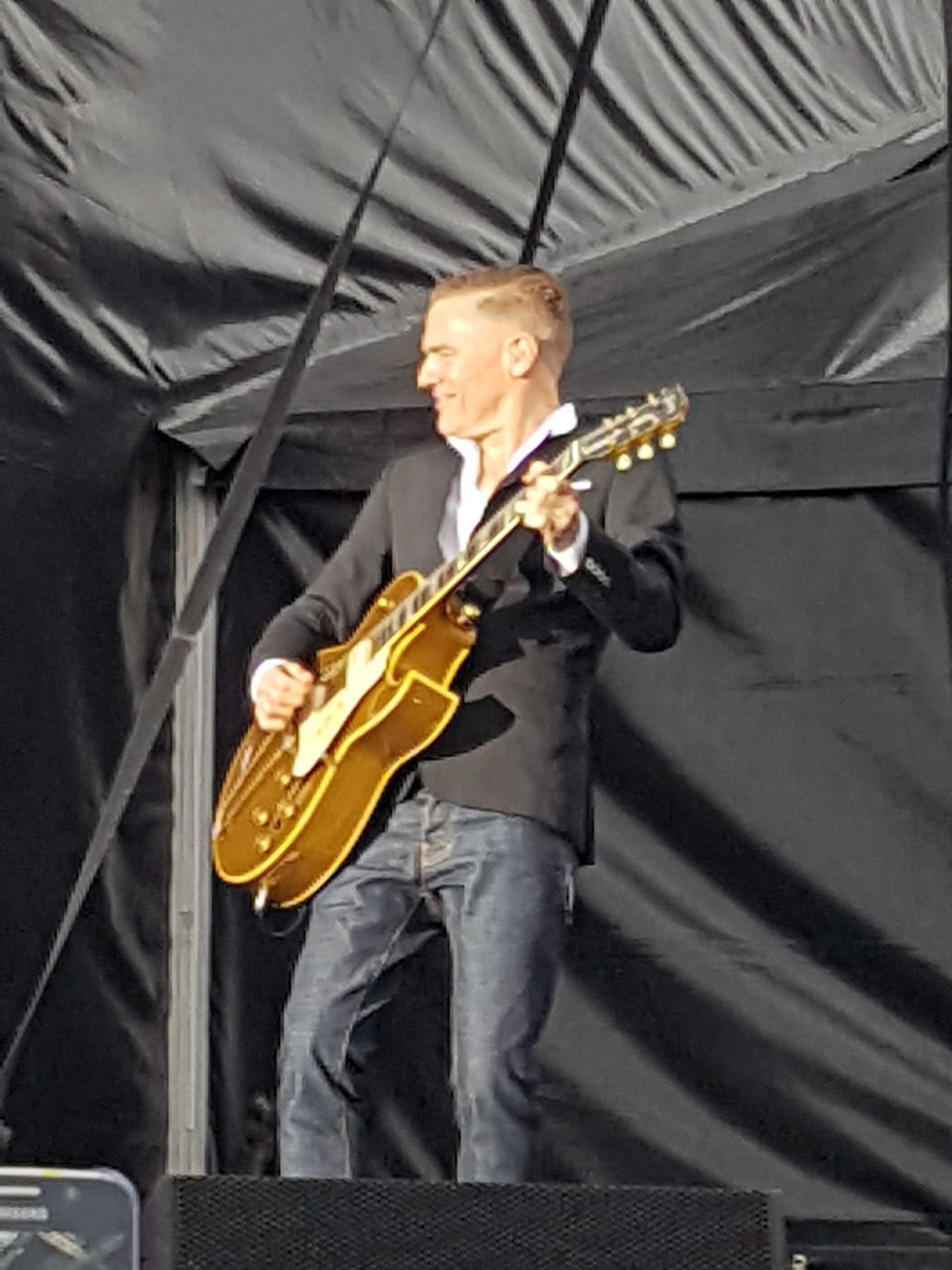 MIDSECTION OF MAN PLAYING GUITAR AT MUSIC CONCERT