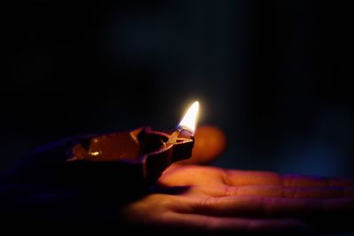 Close-up of hand holding illuminated candle