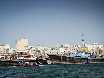 Boats in sea by buildings against clear sky