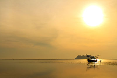 Fishing boat in sea against sky during sunset