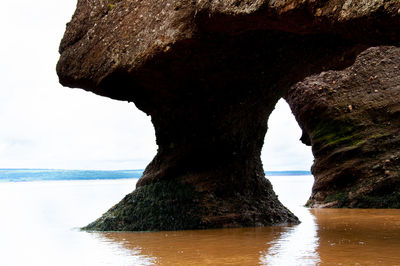 Rock formation on sea shore against sky