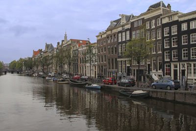 Boats moored in city against sky