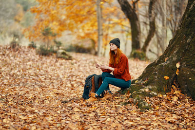 Young woman sitting on leaves during autumn