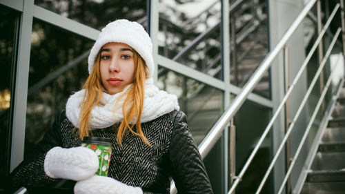 Portrait of young woman wearing warm clothing in city during winter