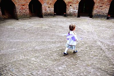 High angle view of girl walking with purple wings on footpath