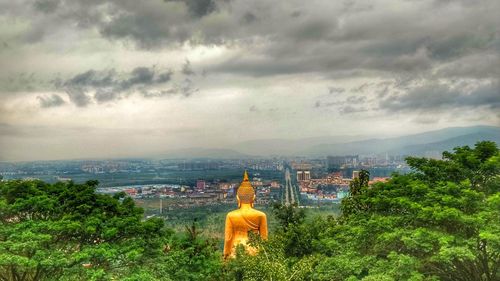 Statue on landscape against sky in city