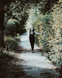 Rear view of woman standing on road in forest