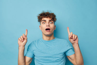 Portrait of young man gesturing against blue background