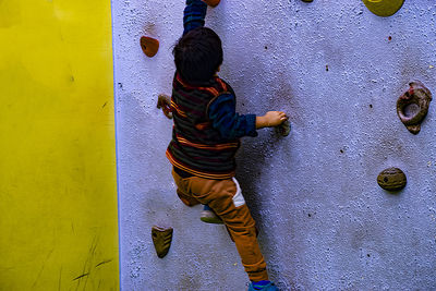 Rear view of boy playing on yellow wall