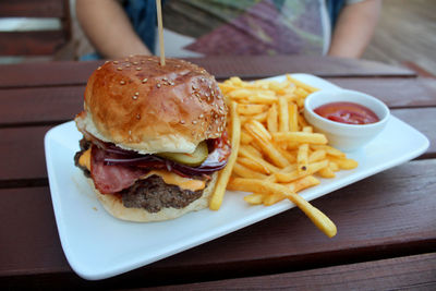 Big cheeseburger with chips on a table in a garden with beautiful view restaurant 