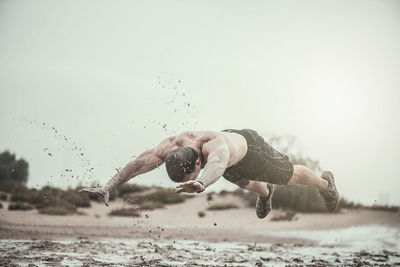 Close-up of athletic man exercising in mud during rainy season