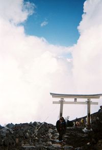 Low angle view of people standing on rock against sky