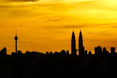 Silhouette petronas tower and kuala lumpur tower against orange sky