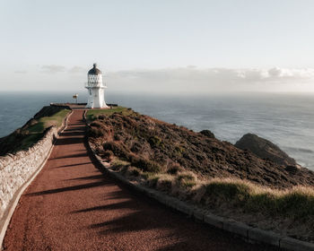 Lighthouse by sea against sky